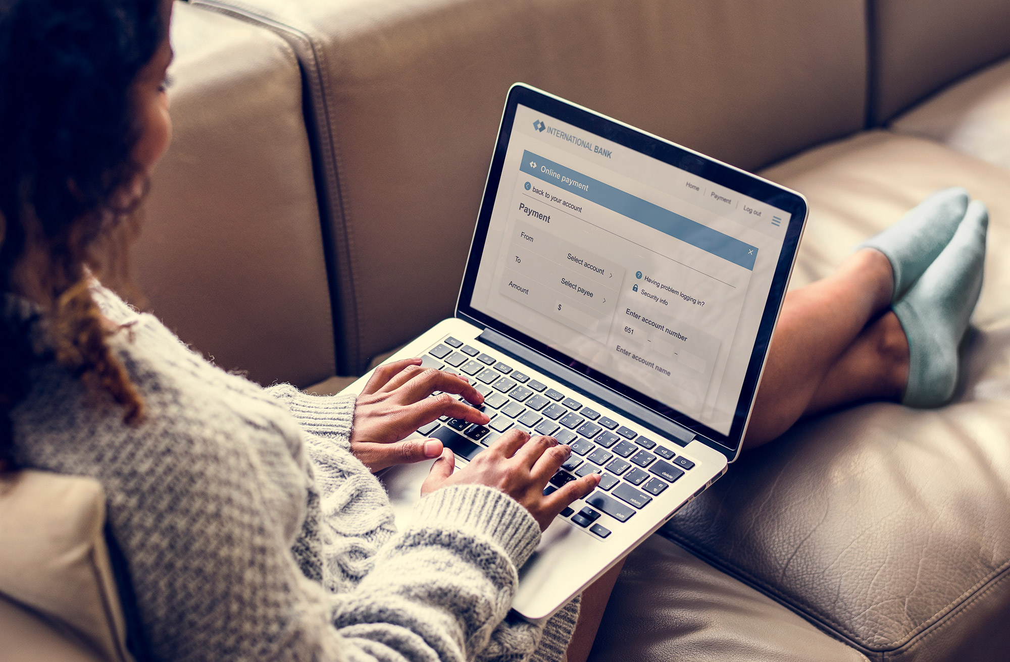 Eine Frau sitzt auf einem Sofa am Laptop